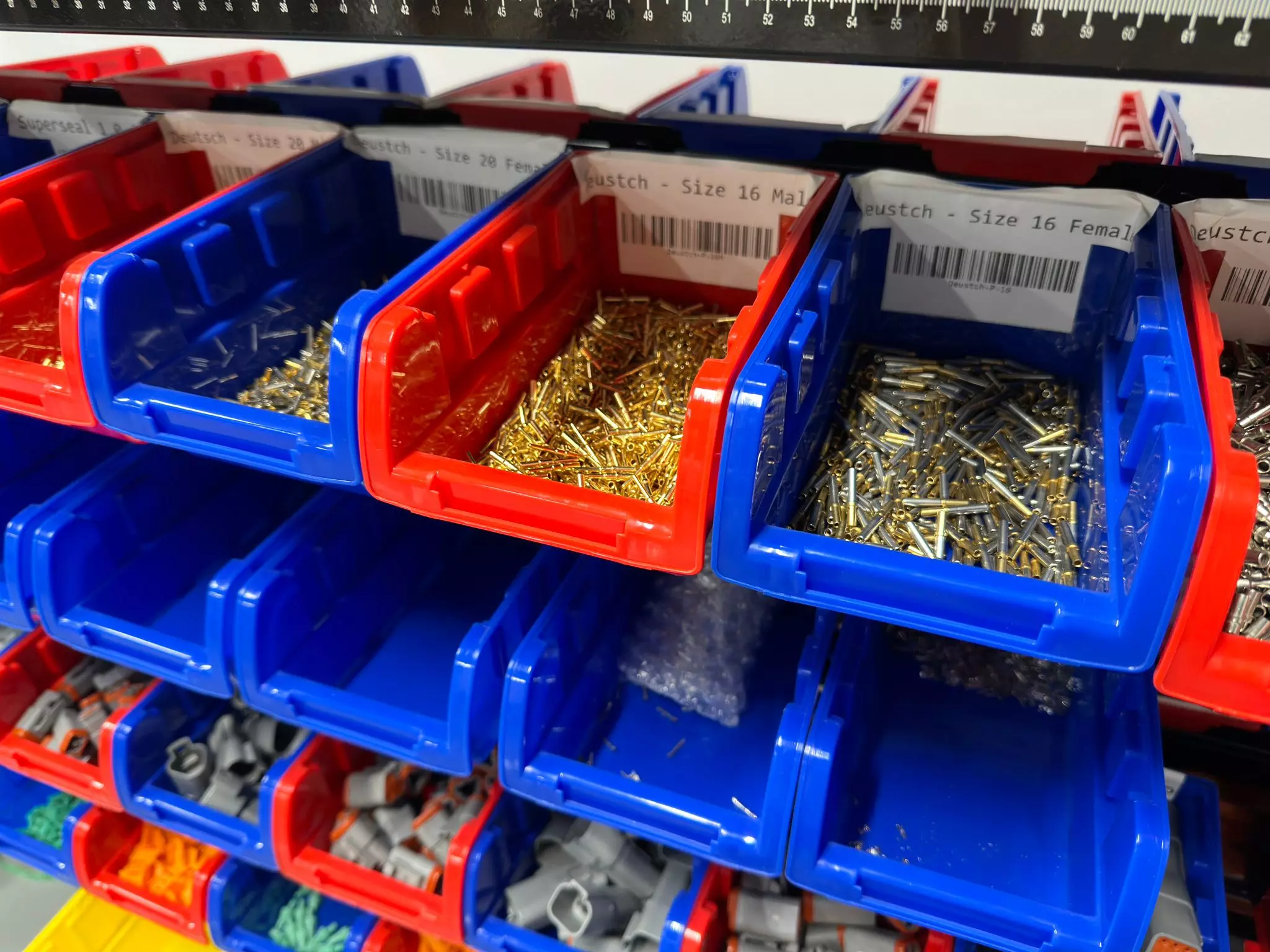 Assorted Deutsch connector pins for electric wiring in blue and red bins at YourSpec.com